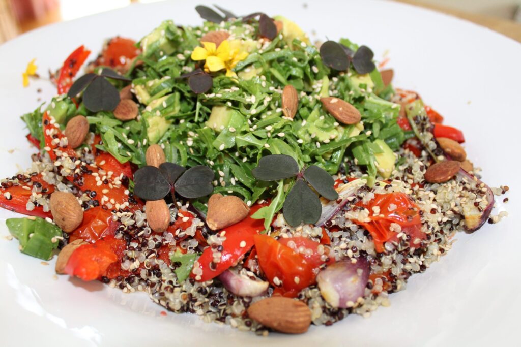 Farvet quinoa med bagte grøntsager, rucolatopping og mandler